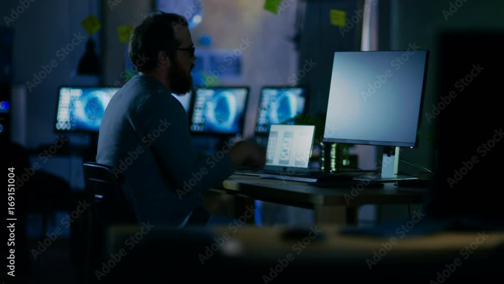 Poster on a early morning mobile application developer sits at his desk and starts working, he is alone in 