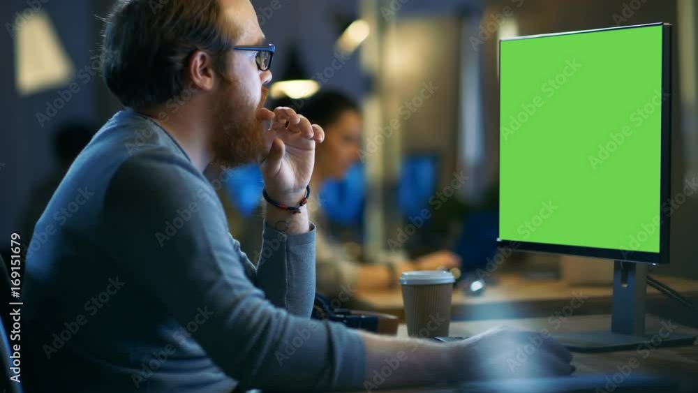 Poster creative bearded man works on a personal computer with isolated mock-up green screen. his office spa