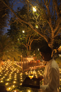 A special 500 Candle Dinner with waiter at dusk. La Residence Phou Vao hotel. Luang Prabang, Laos