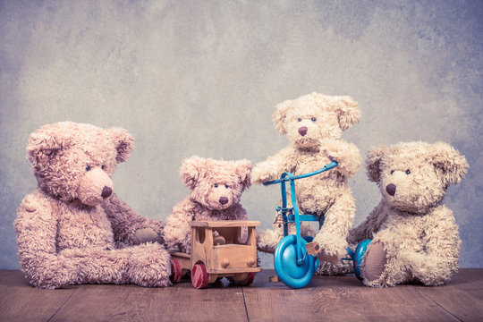 Retro Teddy Bear toys family: parents with kids on vehicles front concrete wall background. Parenthood concept. Vintage instagram old style filtered photo