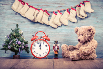 New Year tree, Teddy Bear toy, retro clock and wooden nutcracker front textured wall background...