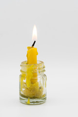 Obraz na płótnie Canvas Old yellow candle lit surrounded with candle wax drop in glass container