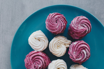 White mango and pink blueberry marshmallows or zephyr with sugar powder on a blue plate. Homemade sweet.