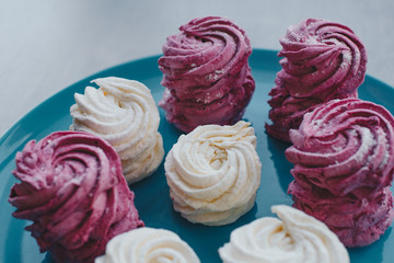 White mango and pink blueberry marshmallows or zephyr with sugar powder on a blue plate. Homemade sweet.