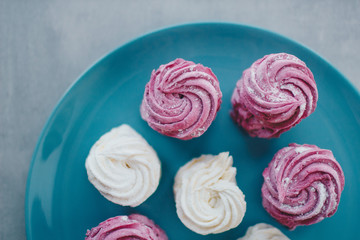 White mango and pink blueberry marshmallows or zephyr with sugar powder on a blue plate. Homemade sweet.