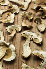 Dry boletus mushrooms on wooden table, background. Vertical.