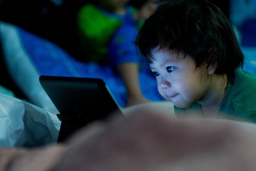 asian children watching tablet on bed