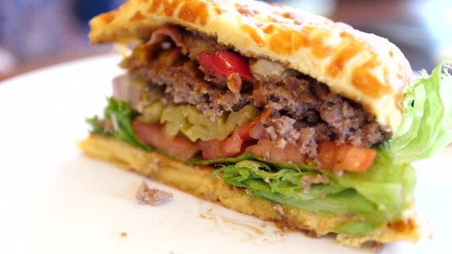 Motion of half bacon gouda burger on plate inside Denny's restaurant