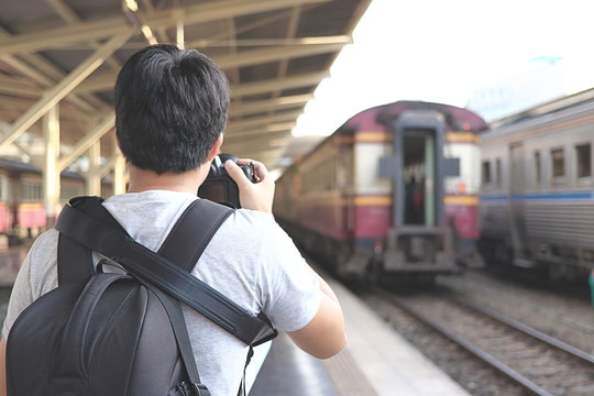 Back view of photographer taking a picture in train station. Selective focus and shallow depth of field.