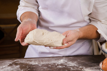 The cook is holding a piece of dough.