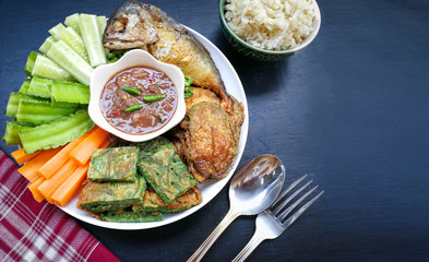 Shrimp paste chili sauce (Nam Prik Kapi) and cooked rice on black wood table. Popular food in Thailand. Thai food flat lay with copy space.