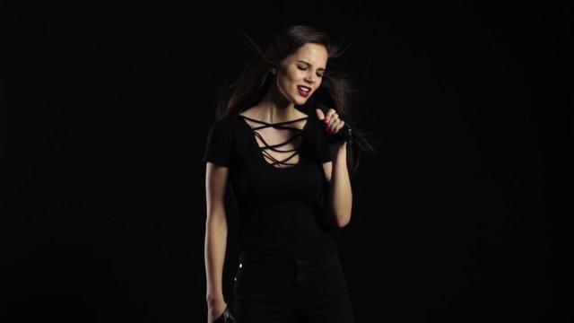 Singer sexually dances and sings songs in a microphone at a concert. Black background. Slow motion