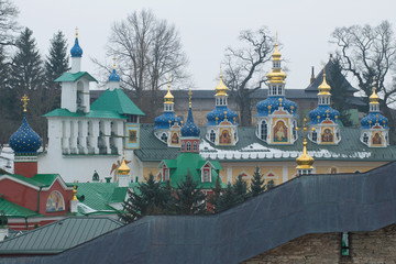 Bell tower and domes of the Syato-Uspensky Pskovo-Pechorsky monastery on the cloudy February day. Pechory, Pskov region. Russia