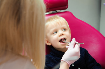 Dentist examining kid's teeth at dental clinic