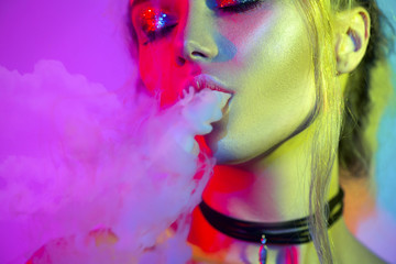 Fashion art portrait of beauty model woman in bright lights with colorful smoke. Smoking girl
