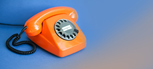 Orange phone blue background. Retro style plastic handset receiver communication call center concept. Shallow depth field. copy space template