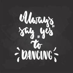 Always say Yes to Dancing - lettering dance calligraphy quote drawn by ink in white color on the black chalkboard background. Fun hand drawn lettering inscription.