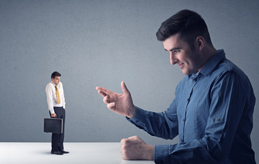 Young businessman fighting with miniature businessman