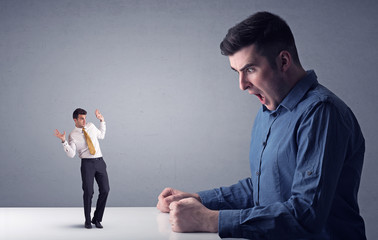 Young businessman fighting with miniature businessman