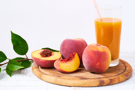Peaches and peach juice on white wood background