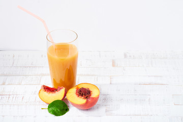 Peaches and peach juice on white wood background