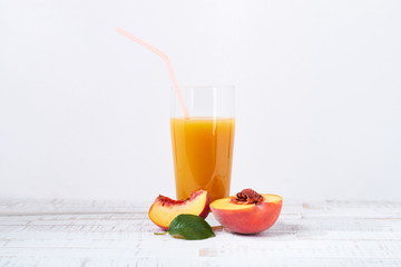 Peaches and peach juice on white wood background