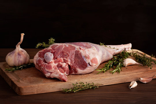 Fresh raw lamb leg ready for roasting with garlic and herbs