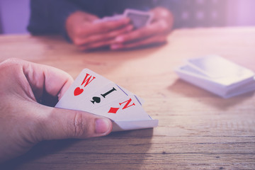 man's hand revealing four cards on the table. win the game concept
