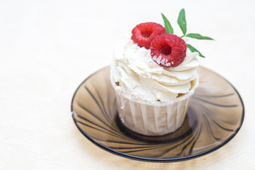 Cake with cream and raspberries on a glass plate