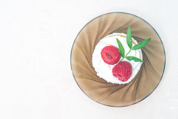 Cake with cream and raspberries on a glass plate