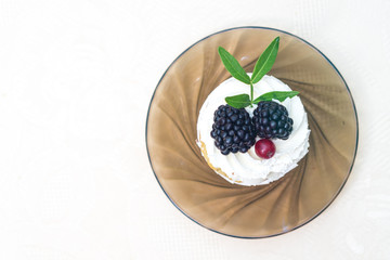 Cake with cream and blackberries on a glass plate