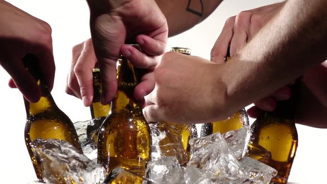 Bottles of beer in the ice, a company of friends pull them out. White background. Close up