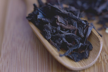 Black leaf tea in a wooden spoon