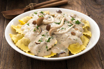 Plate of ravioli with cream sauce on wood table

