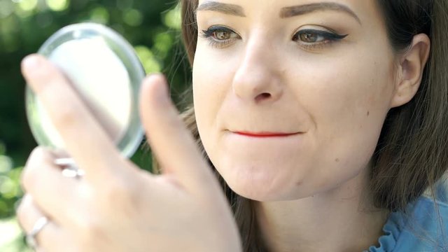 Attractive woman applying red lipstick on her lips, steadycam shot
