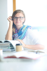 Young woman sitting at a desk among books. Student