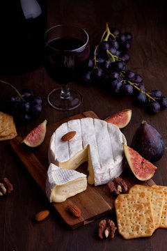 French cheese camembert with glass of red wine, grapes and figs