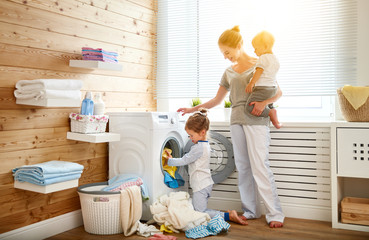 Happy family mother   housewife and children in   laundry load washing machine