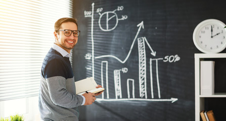 Happy male student, teacher, freelancer with chalk at blackboard