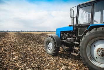 Obraz premium Old blue tractor in a empty field. Agricultural machinery, field work.