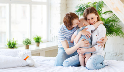 Obraz premium Happy family mother father and baby in bed