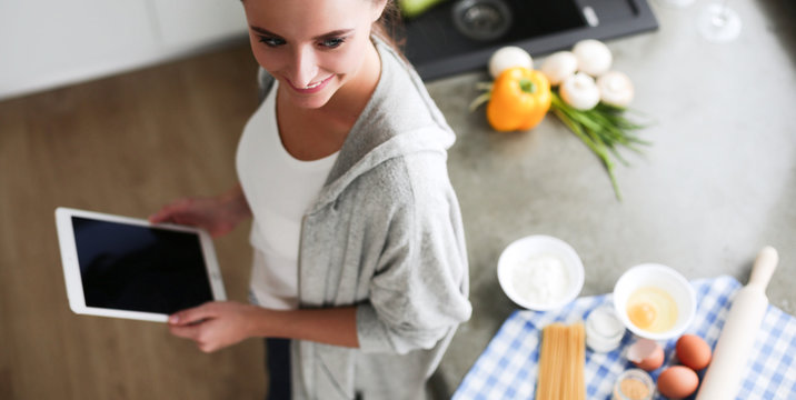 Woman Baking At Home Following Recipe On A Tablet