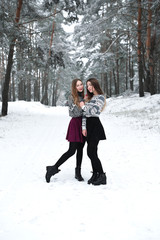 Fototapeta na wymiar Two young teenage hipster girl friends together.Close up fashion portrait of two sisters hugs and having fun winter time,wearing sweater,best friends couple outdoors, snowy weather