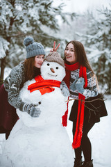 Close up fashion portrait of two sisters hugs and having fun winter time,wearing pink hats, rabbit ears and sweater,best friends couple outdoors, snowy weather