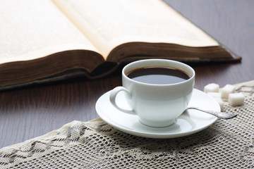 Cup of coffee on table with book