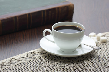 Cup of coffee on table with book