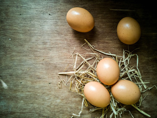 Fresh chicken egg with straw nest on rustic wood table with copy space for text. High protein food.