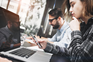 Photo of close-up of beautiful business woman with smartphone in her hand working behind laptop in loft office. Work for electronic devices. Digital business team have meeting in office