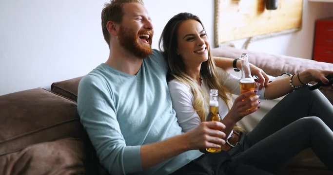 Beautiful couple in love watching tv and drinking