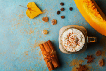 Pumpkin spiced latte or coffee in cup decorated cinnamon on turquoise vintage table top view....